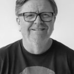 black and white headshot of a man in a t-shirt and glasses